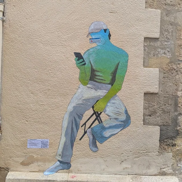 Collage sur un mur de pierre, personnage assis sur une marche, un téléphone à la main.