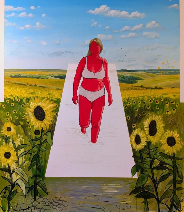 Femme en maillot rouge marchant sur un chemin rose au milieu d'un champ de tournesols.